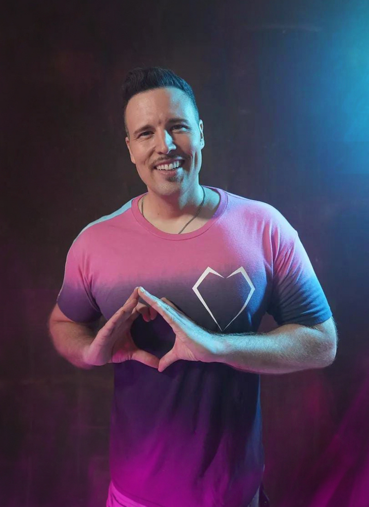 A man posing with his hands in a heart shape wearing the GFL x TimTactics Exclusive T-Shirt by GFLApparel.
