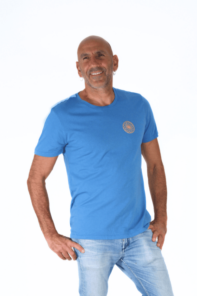 Man smiling while posing with hands on hips, wearing a blue Lotus of Life Tee by GFLApparel and jeans against a white background.