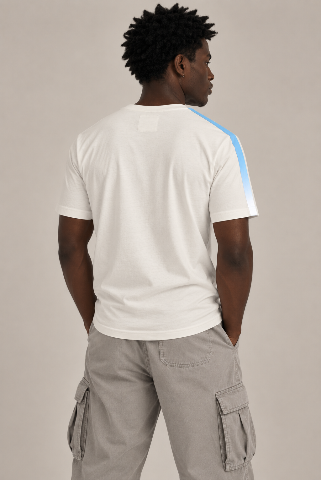 A man shown from the back wearing a white short-sleeve t-shirt with a light blue stripe detail on the right shoulder, paired with light gray cargo pants, against a solid light gray background.