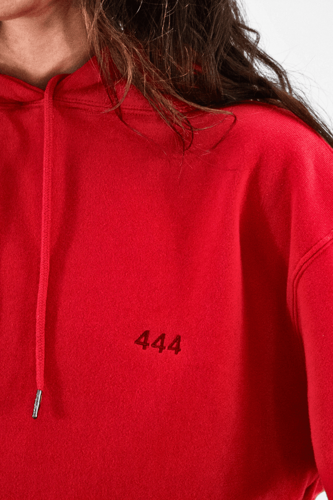 A close-up of a person in a GFLApparel Angel Number 444 Hoodie, symbolizing a spiritual journey with the number "444" embroidered in black on the fabric.
