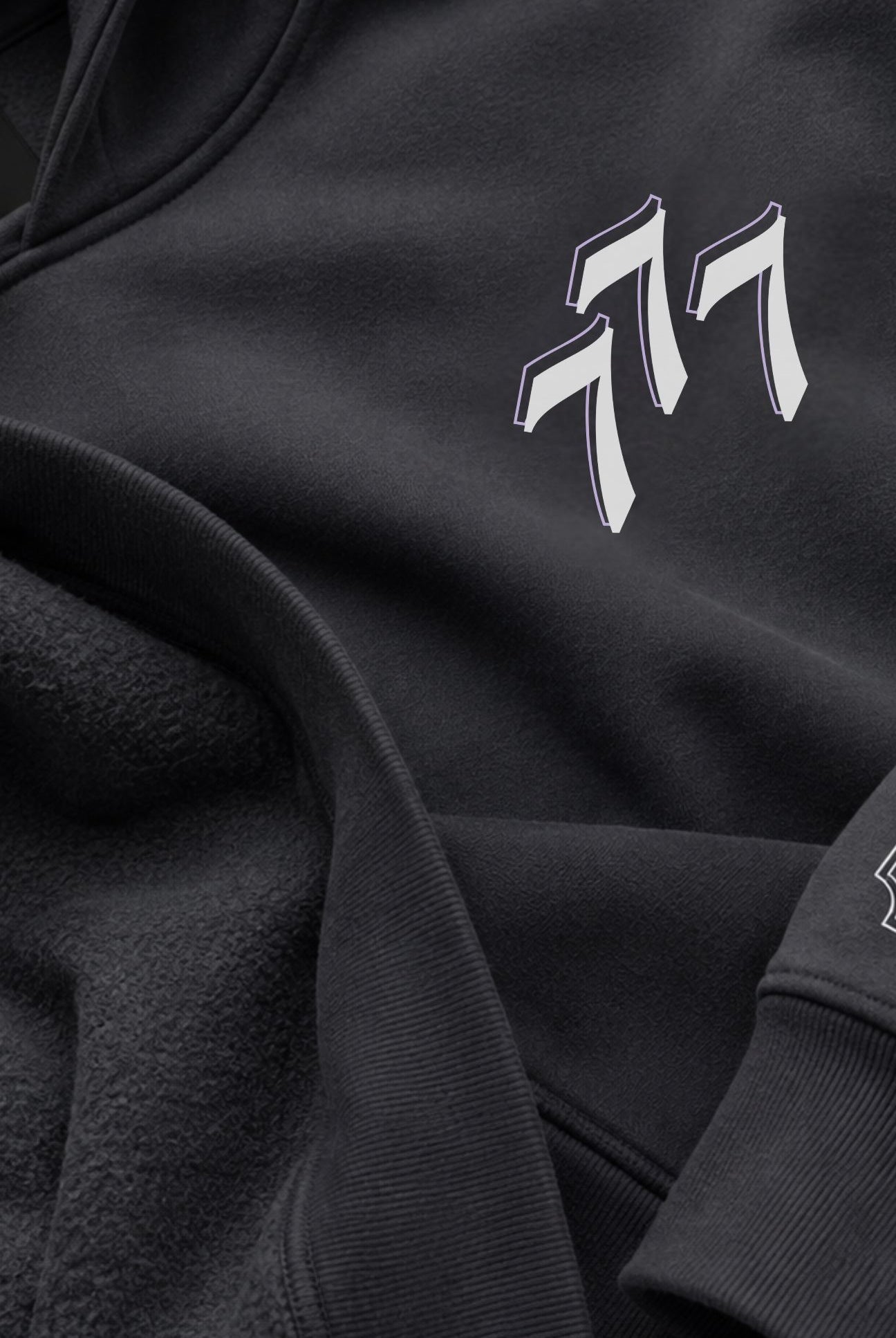 Close-up of a asteroid color fleece and cotton hoodie featuring a stylized white and gray 777 logo on the chest.