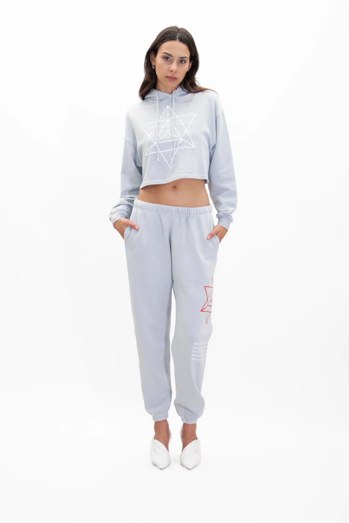 The model is wearing a MERKABA cropped hoodie in galactic gray and joggers from GFLApparel.