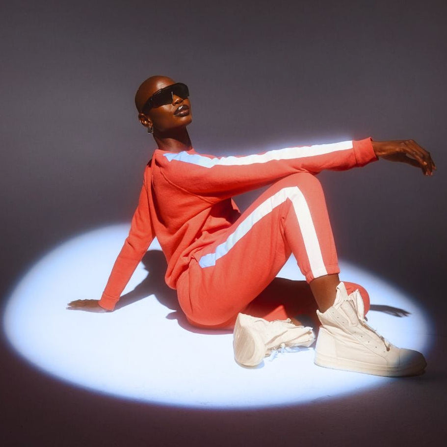 Person wearing a red tracksuit with reflective elements sitting on a dark background