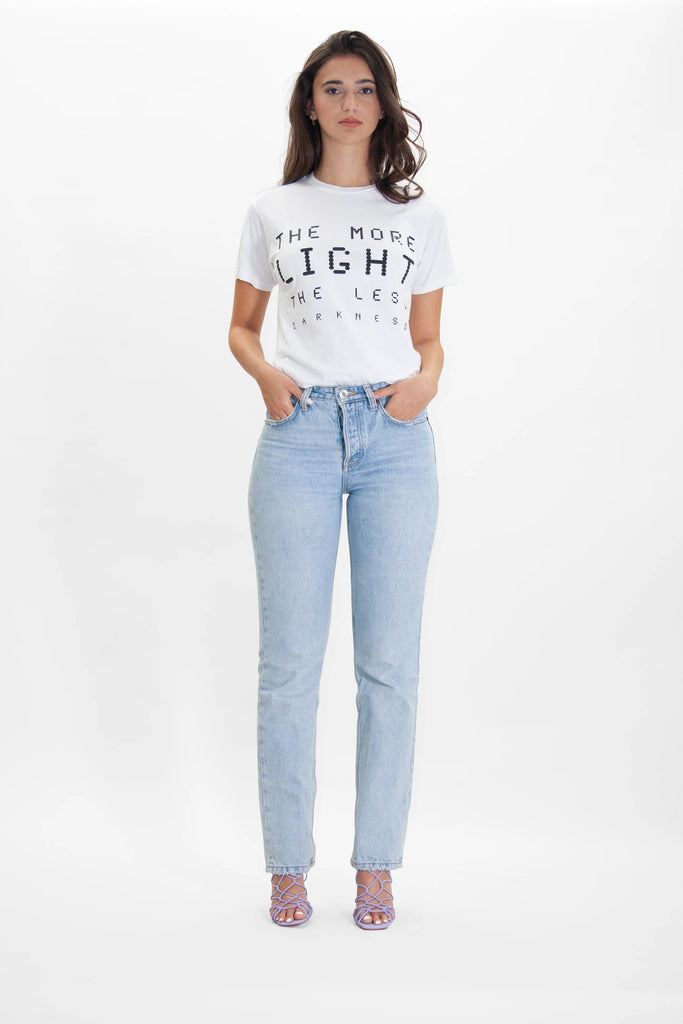 A woman wearing a MORE LIGHT TEE IN LITE BEAM t-shirt and jeans from GFLApparel.