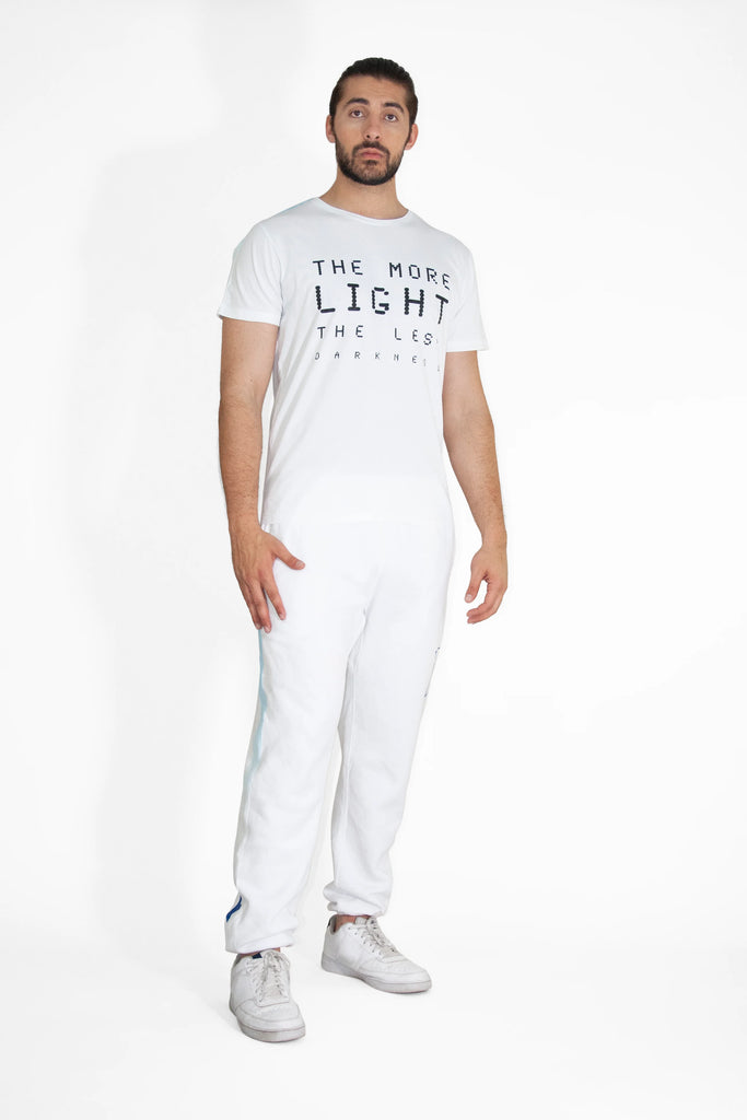 A man wearing the MORE LIGHT TEE IN LITE BEAM by GFLApparel, and jogging pants.