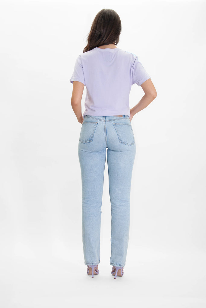 The back view of a woman wearing GFLApparel's MORE LIGHT TEE IN NEBULA light blue jeans.