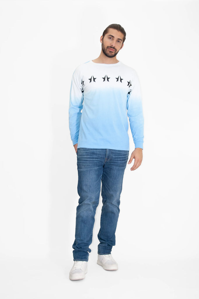 A man wearing GFLApparel jeans and a GFL STARS L/S IN ATMOSPHERE blue long-sleeved t-shirt.