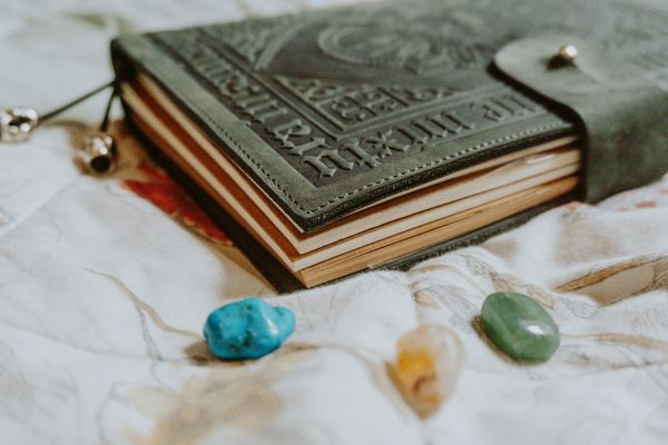 Vintage leather-bound book with embossed text on a textured surface with stones.