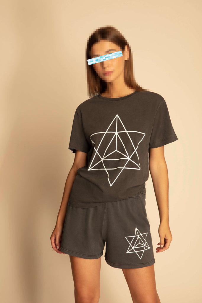 A woman wearing a MERKABA SHORTS IN SPACE GLOW t - shirt and shorts with a geometric design from GFLApparel.