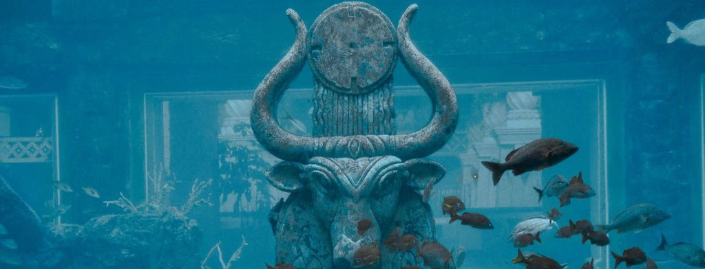 Tropical fish swim past a statue in a sunken city
