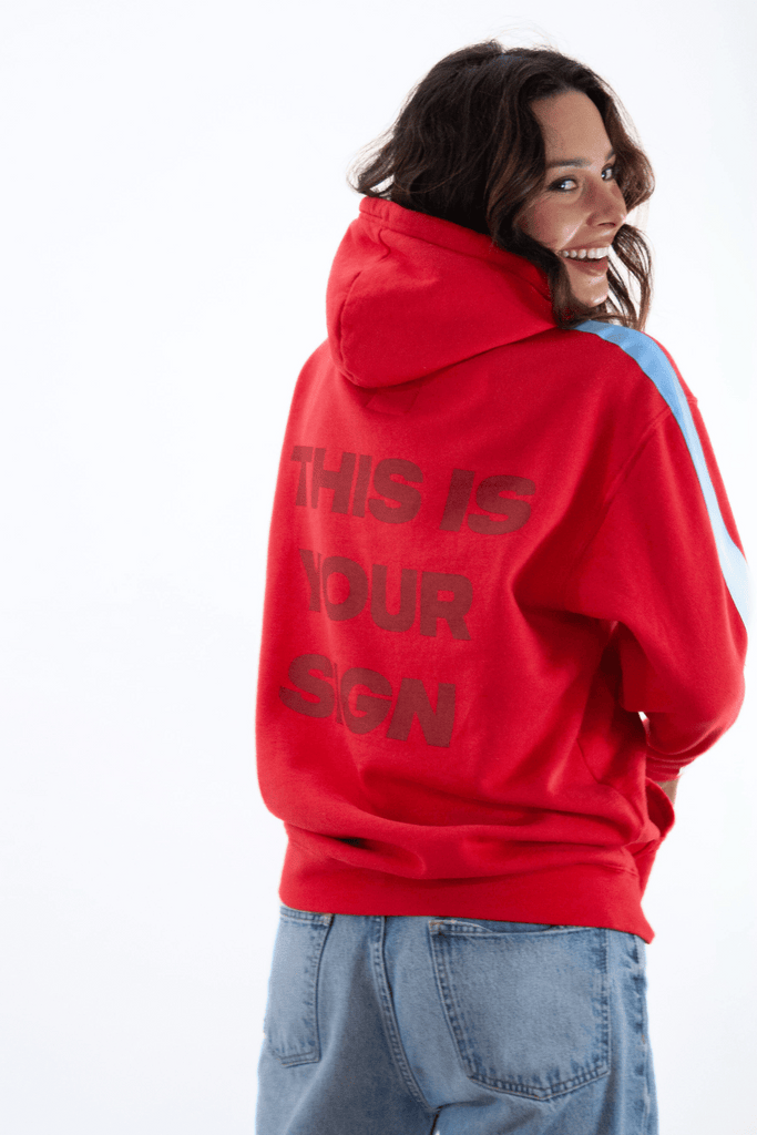 Woman in a red GFLApparel Angel Number 444 Hoodie, symbolizing her spiritual journey, facing the camera over her shoulder.