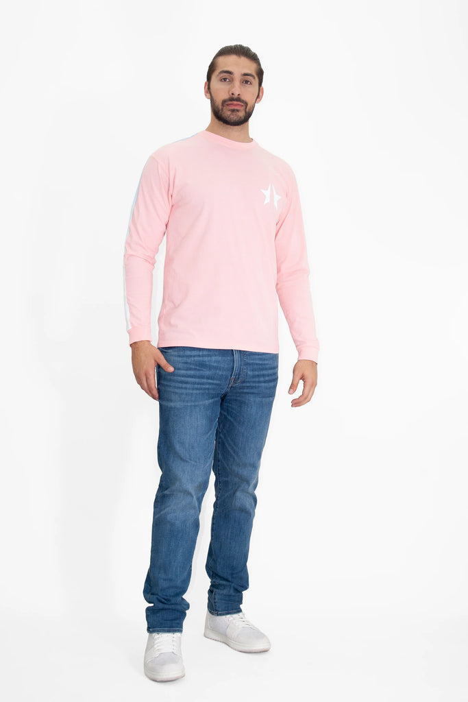 A man wearing a pink GFLApparel 369 L/S IN SUNFADE long sleeve t - shirt and jeans.