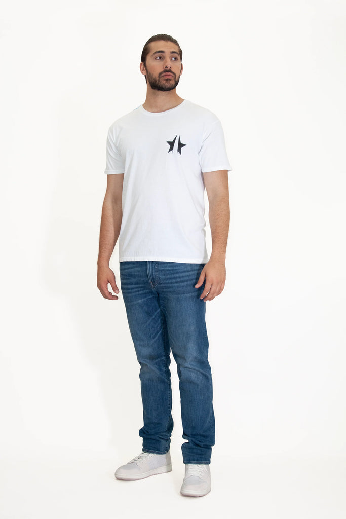 A man wearing a white 369 Tee in Lite Beam t - shirt and jeans from GFLApparel.