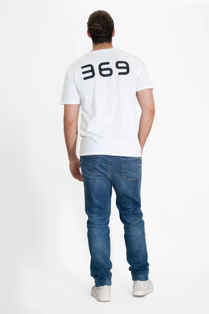Rear view of a person wearing the GFLApparel 369 Tee in Lite Beam with Nikola Tesla's sequence "369" printed in black on the back, paired with blue jeans and white shoes.