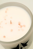 The Galactic Federation of Light Ascension Candle features a white candle made from non-carcinogenic soy wax with a single wick and scattered pink salt crystals on top, all housed in a frosted glass container.