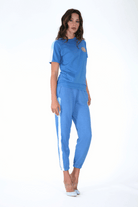 Woman posing in a blue tracksuit with white stripes, embodying the interconnectedness of sacred geometry, and Lotus of Life Tee by GFLApparel.