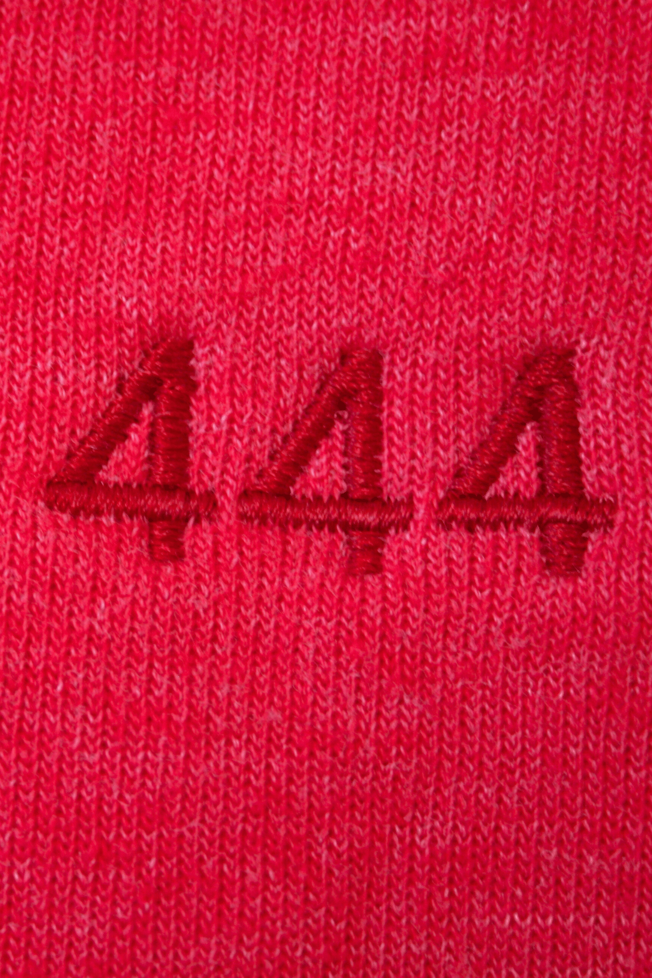 Close-up of red fabric with triple 'a' embroidery in matching thread, symbolizing Angel Number 444 Women's Pants by GFLApparel and divine intention.