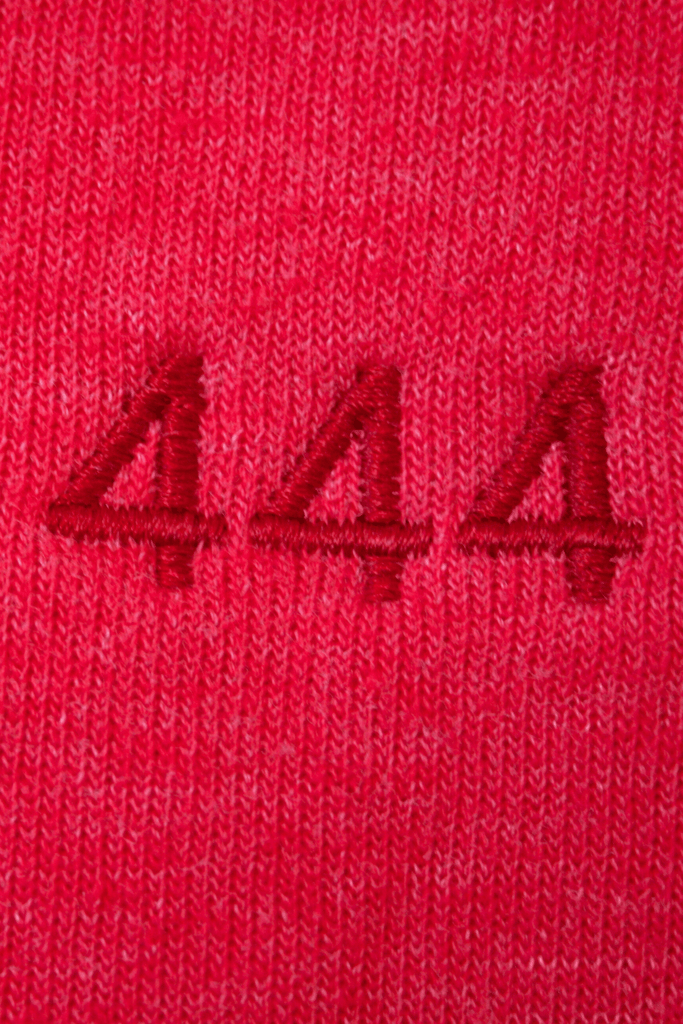 Close-up of red fabric with triple 'a' embroidery in matching thread, symbolizing Angel Number 444 Women's Pants by GFLApparel and divine intention.