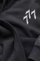 Close-up of a asteroid color fleece and cotton hoodie featuring a stylized white and gray 777 logo on the chest.