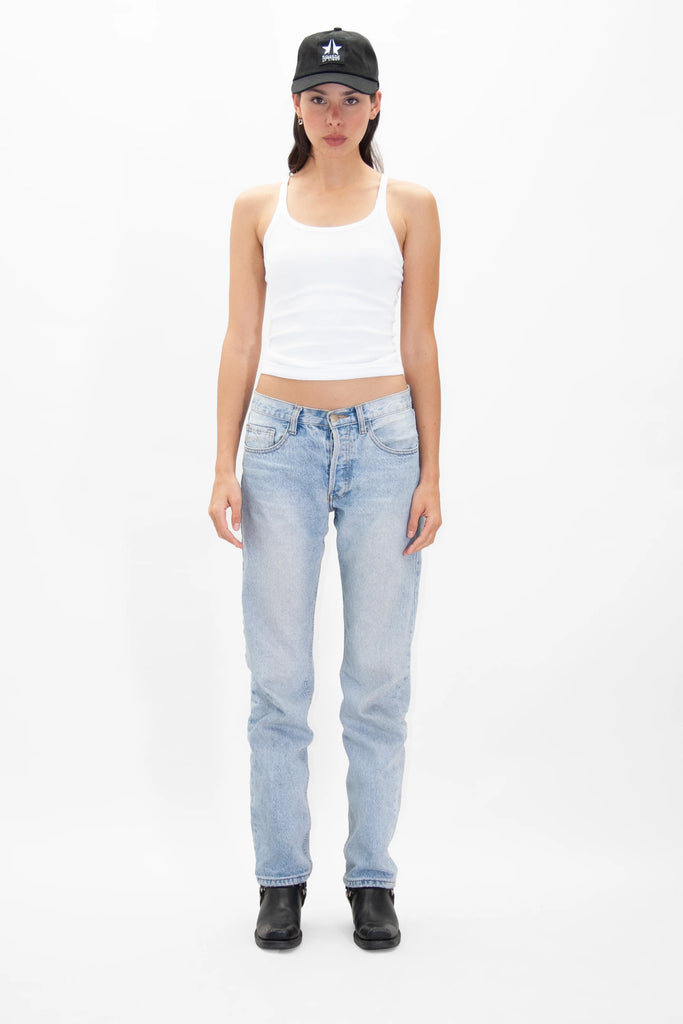 A person wearing a must-have GFL Baseball Cap by GFLApparel, a white tank top, light blue jeans, and black boots stands against a white background.