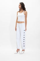 A woman wearing white sweatpants and a GFL Tank Top in Lite Beam by GFLApparel.