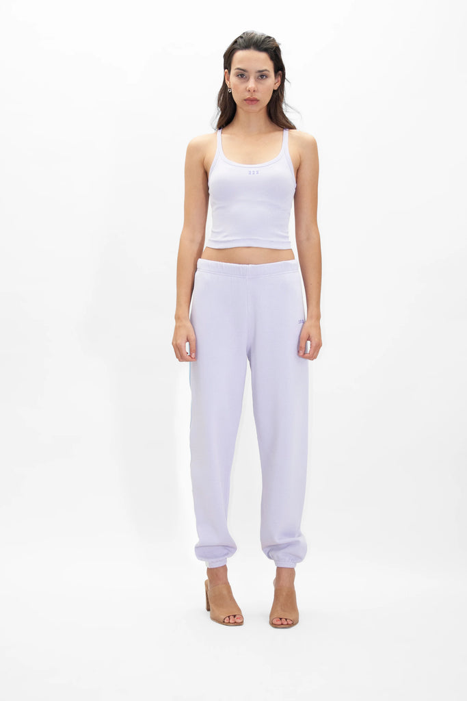 A woman wearing a white Angel Number 222 Cropped Tank in Nebula by GFLApparel and joggers in lilac.