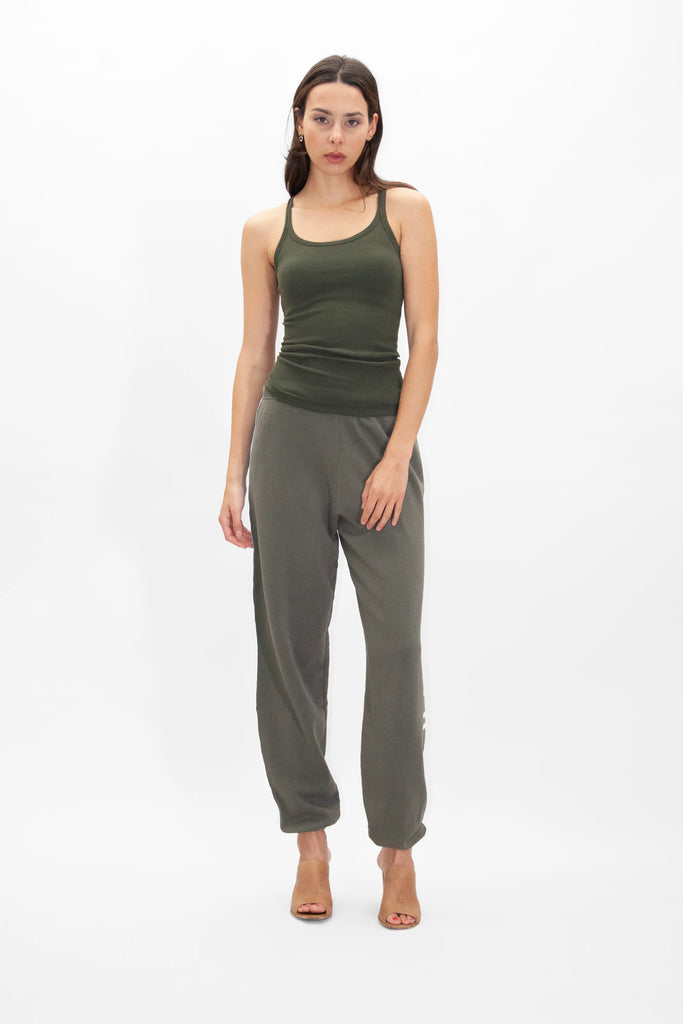 A woman wearing a GFL Tank Top in Caladan and joggers in olive green.
