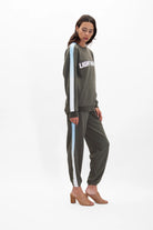 A person wearing a dark sweatshirt with the word "LIGHTWORK" on the chest, paired with matching Galactic Sweatpants in Caladan by GFLApparel that have light blue and white stripes down the sides, and tan heeled shoes.