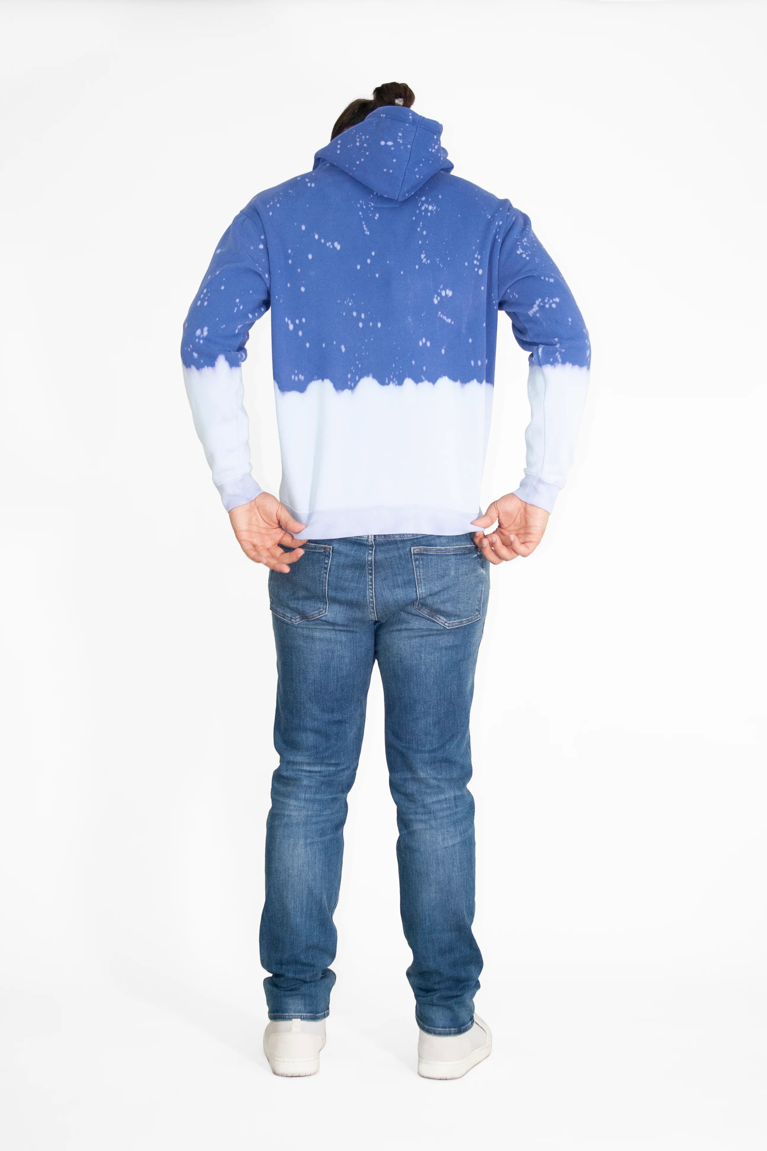 Person with long hair wearing a Limited Edition Light Worker Hoodie in Indigo Child by GFLApparel, blue jeans, and white shoes, standing with their back to the camera in front of a plain white background.