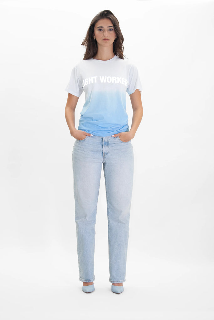 A woman wearing jeans and a white LIGHT WORKER TEE IN ATMOSPHERE - GFLApparel t - shirt.