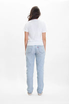 A person stands facing away from the camera, showcasing the Light Worker Tee in Lite Beam by GFLApparel in soft breathable cotton. They are wearing light blue jeans and sneakers against a plain white background.