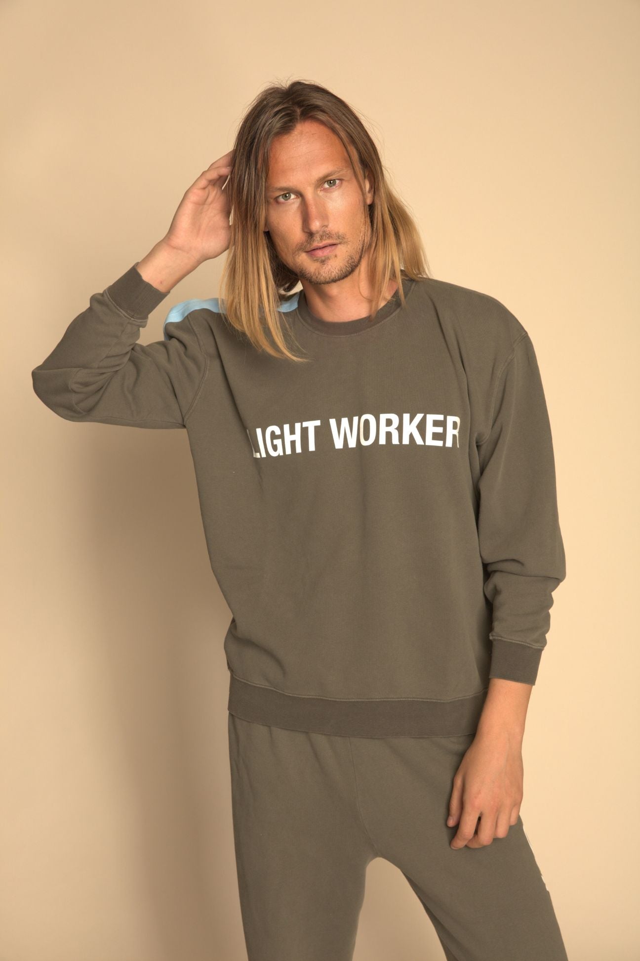 Man wearing a 'IGHT WORKER' sweatshirt against a beige background