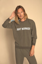 Man wearing a 'IGHT WORKER' sweatshirt against a beige background