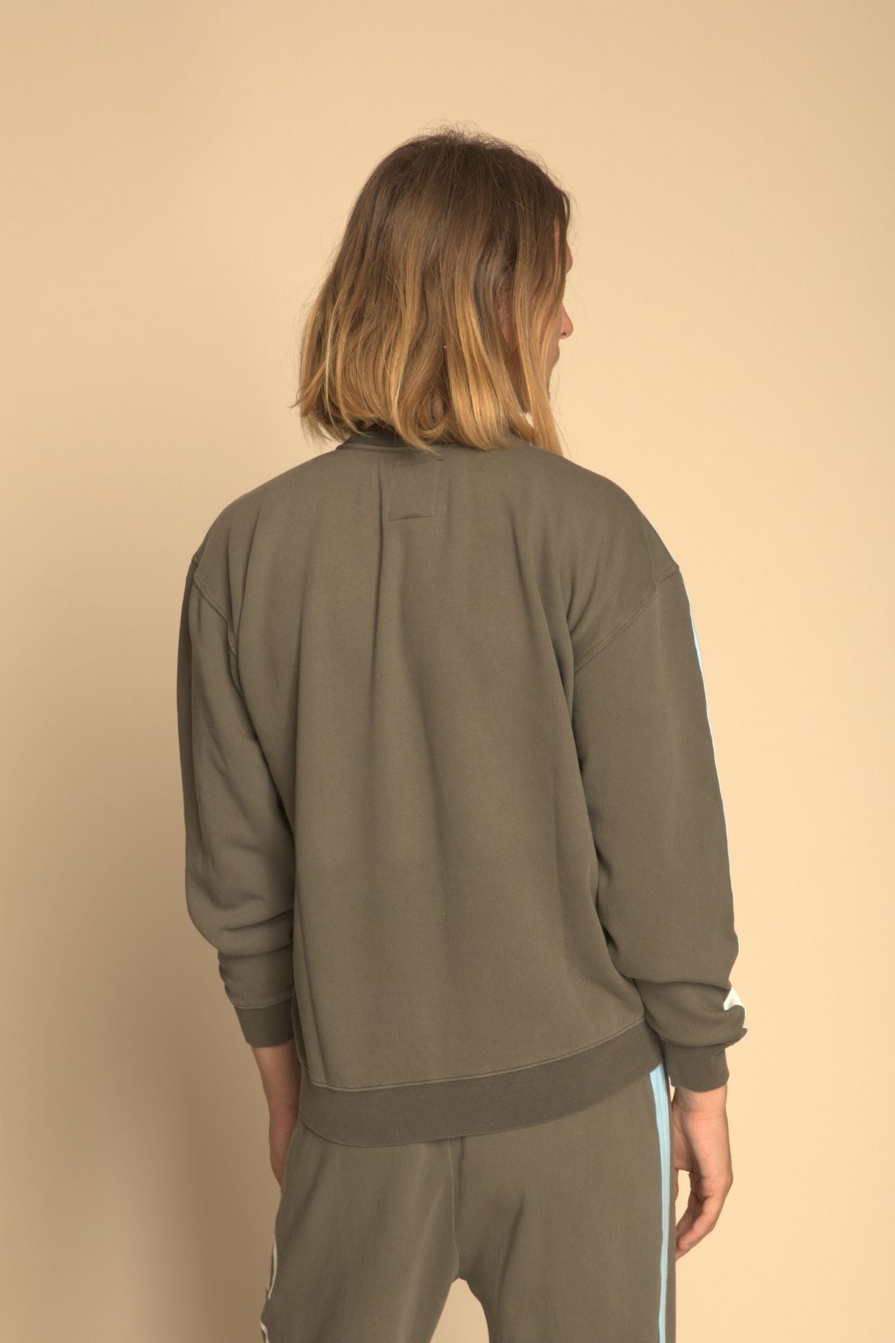 Person wearing a green tracksuit against a beige background