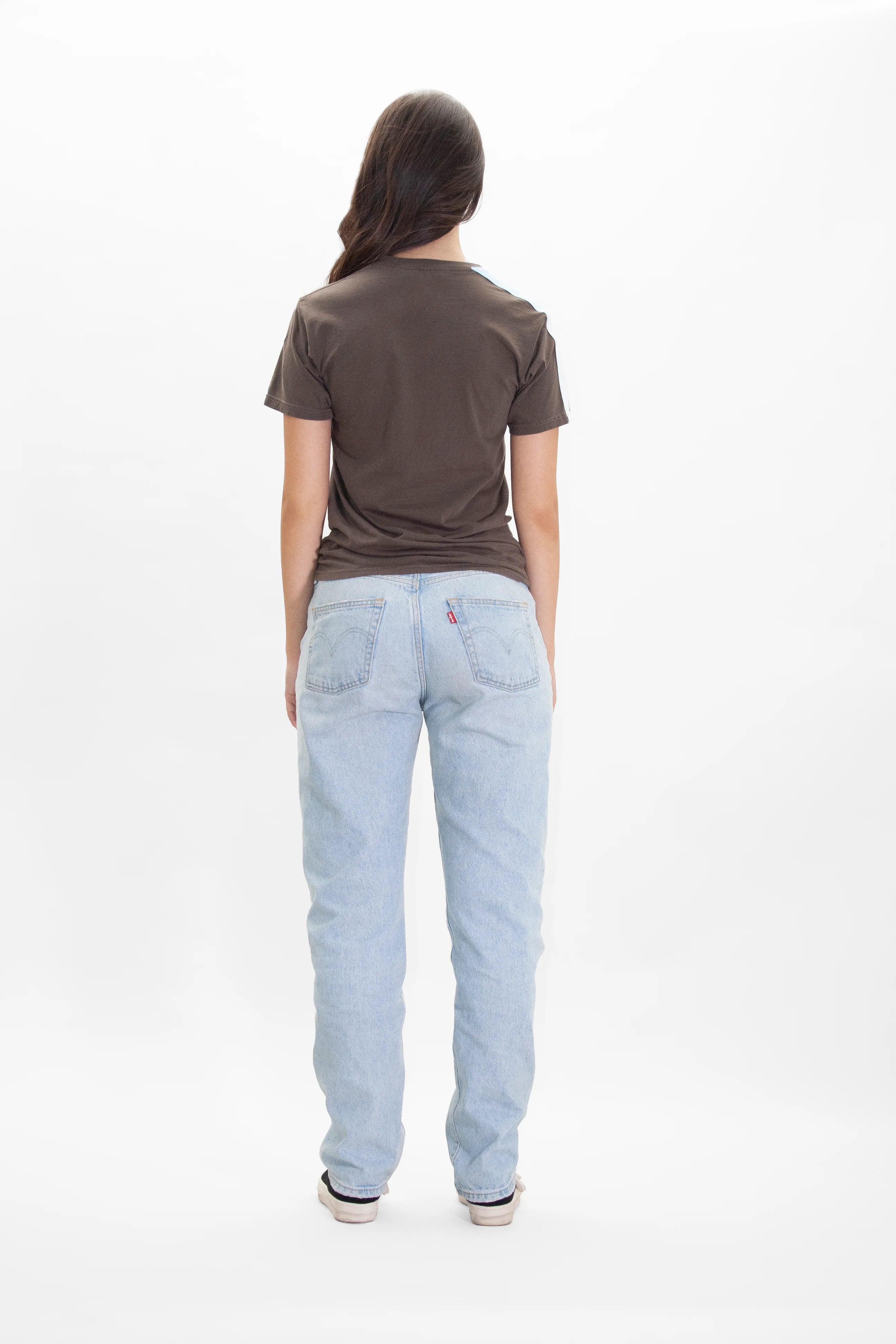 The back view of a woman wearing GFLApparel's MERKABA TEE IN EARTH jeans.