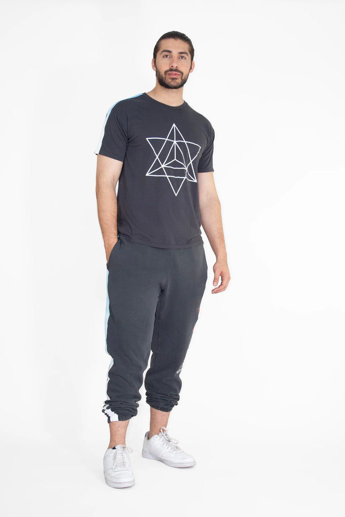 A man wearing a MERKABA TEE IN SPACE GLOW t-shirt and grey sweatpants from GFLApparel.