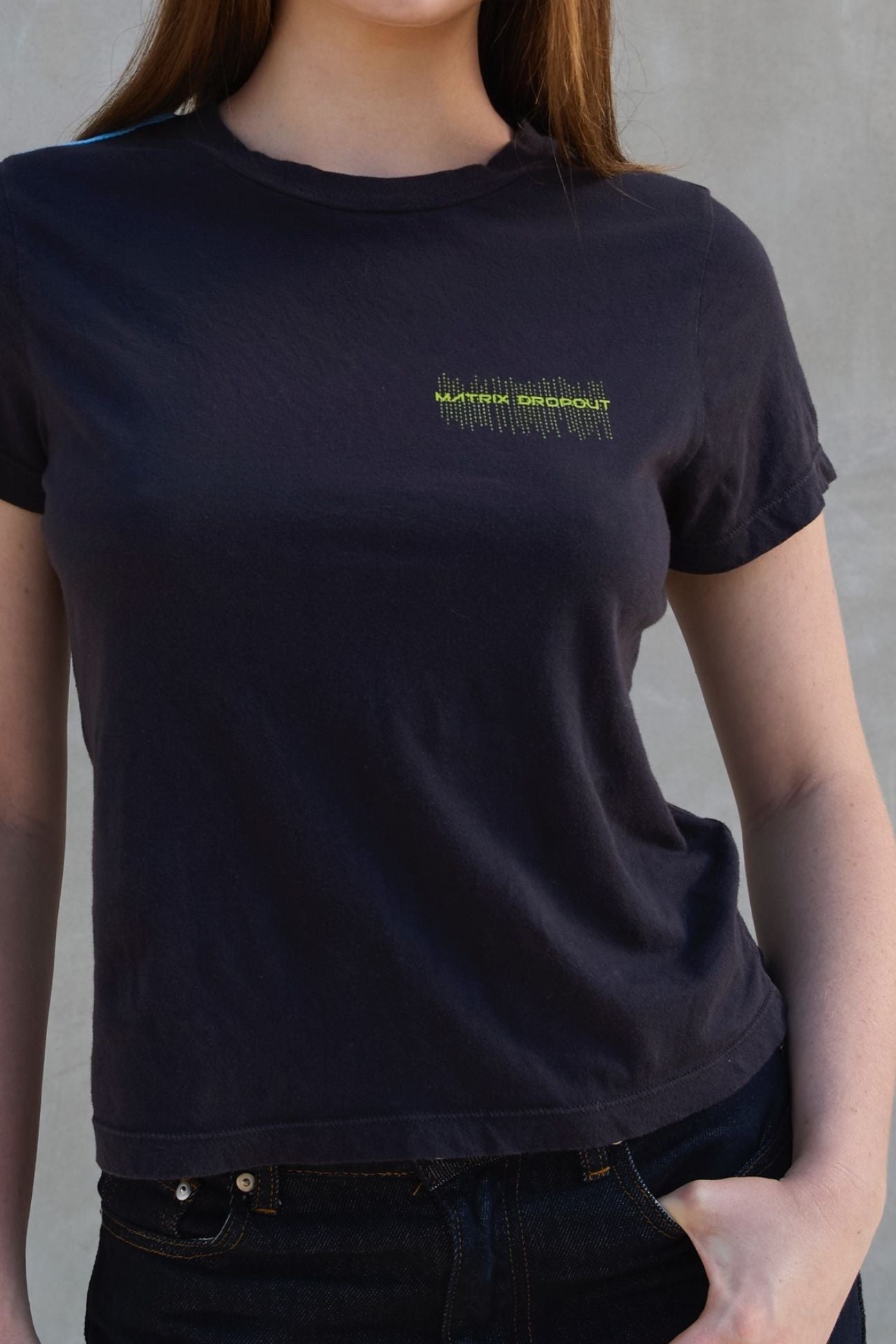 Person wearing a black t-shirt with neon text on a plain background