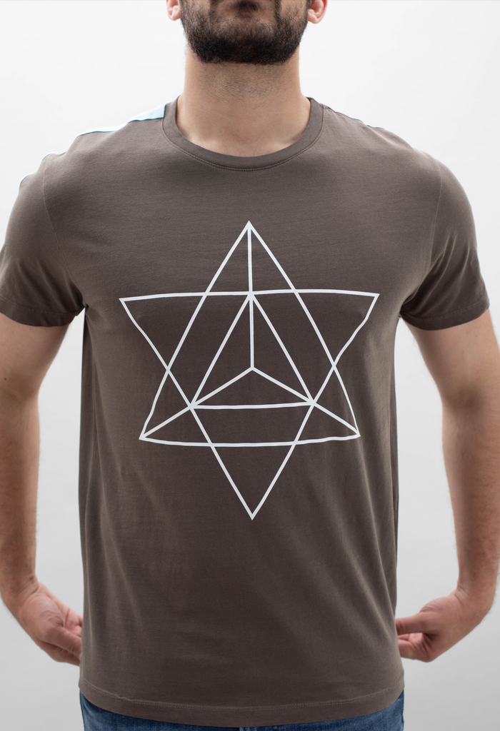 A man wearing a GFLApparel Merkaba Tee in Earth with a geometric design on it.