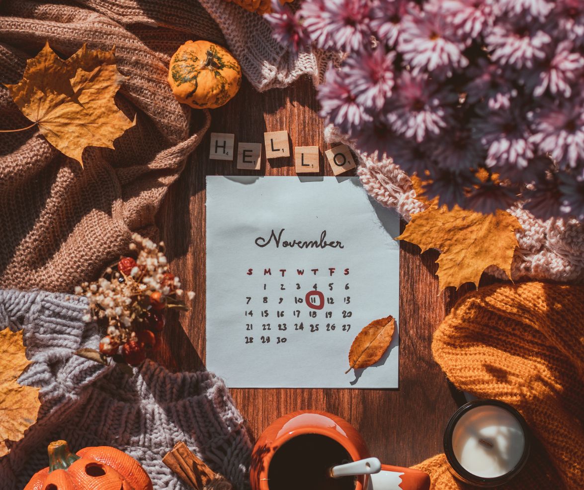 Calendar for November surrounded by autumn decorations on a wooden surface