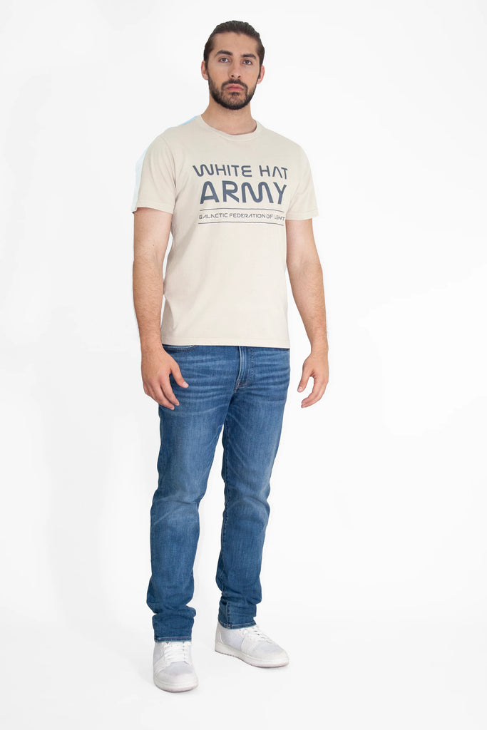 A man wearing a GFLApparel WHITE HAT ARMY TEE IN DUNE and jeans.