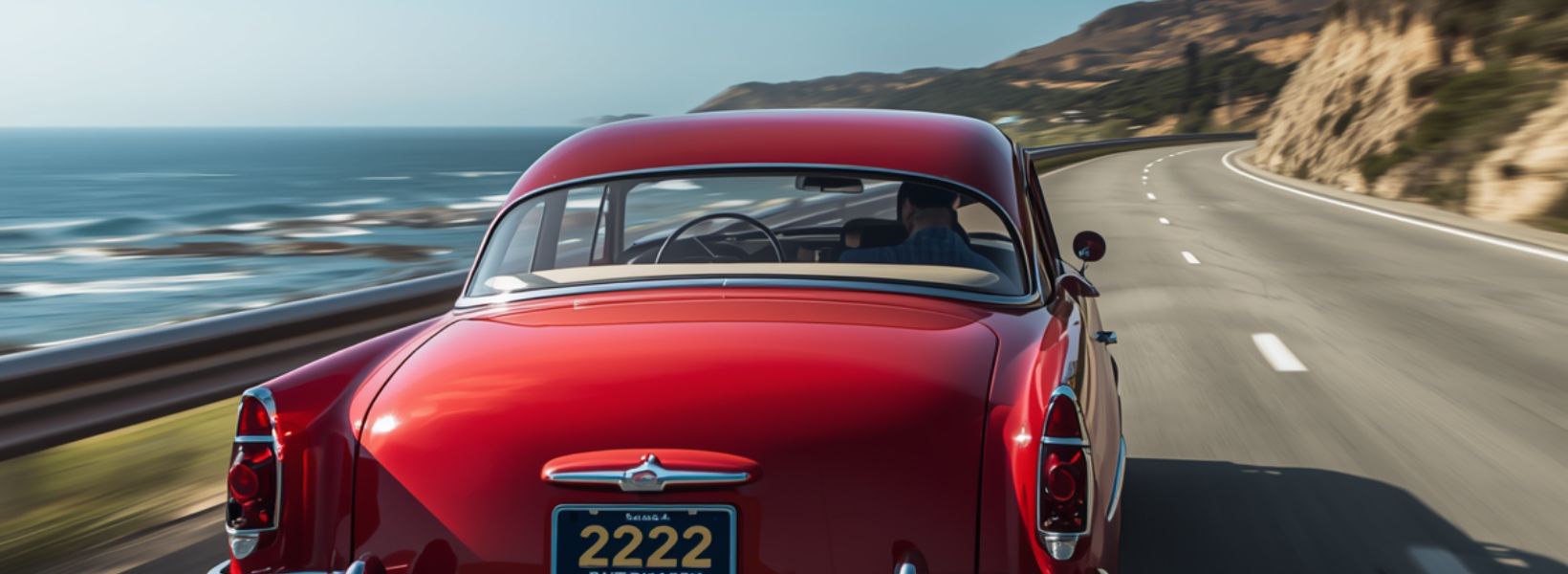 a classic red car with a license plate reading 2222 driving down the pacific highway