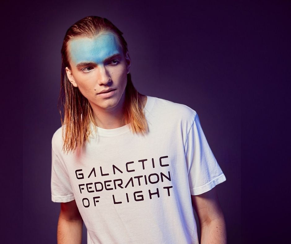 Person wearing a white t-shirt with 'Galactic Federation of Light' text against a dark background
