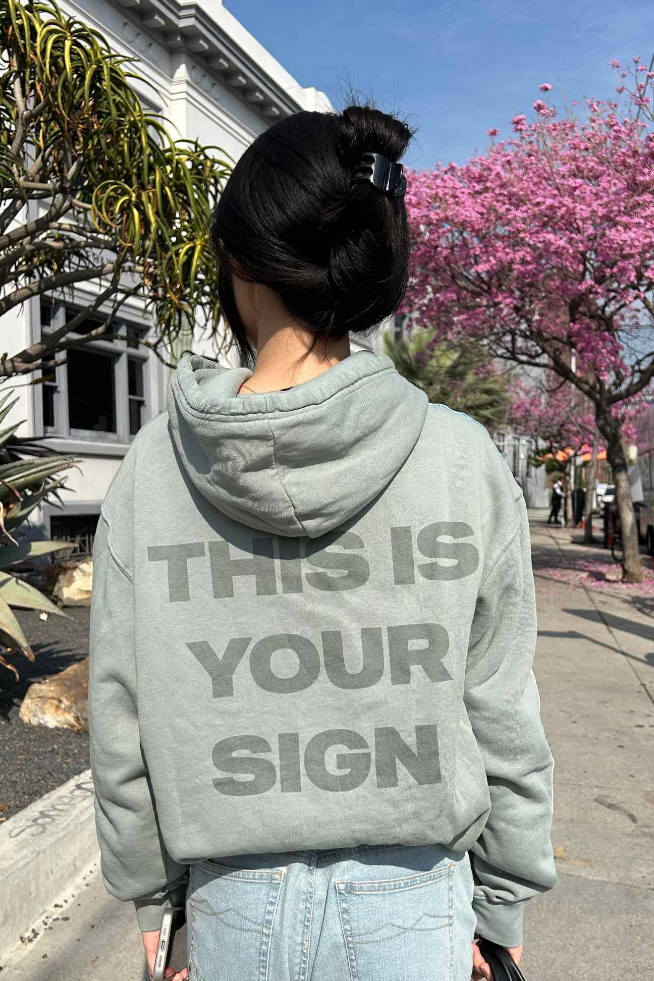 Woman in a gray, high-quality cotton-blend hoodie with the text 