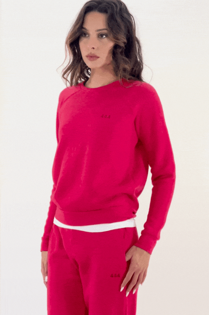 Woman posing in a red tracksuit with white trimmings, symbolizing divine comfort through GFLApparel's Angel Number 444 Women's Crewneck.