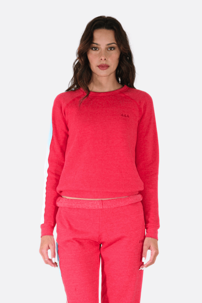 Woman wearing a red sweatshirt and pants, radiating comfort under the divine protection of GFLApparel's Angel Number 444 Women's Crewneck.