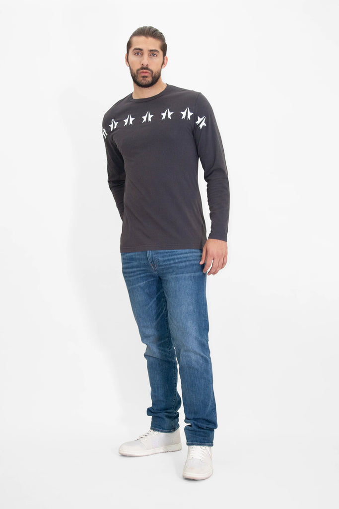 A man wearing a GFLApparel GFL STARS L/S IN SPACE GLOW t-shirt and jeans.
