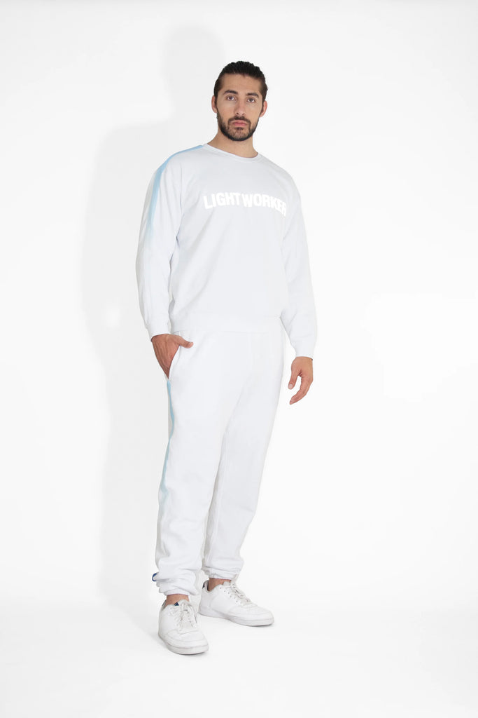 A man wearing a white LIGHT WORKER CREWNECK IN LITE BEAM sweatshirt and white jogging pants from GFLApparel.