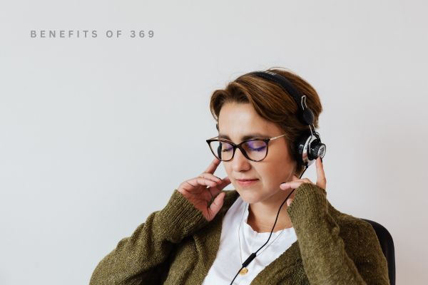 Woman wearing headphones and glasses, sitting with a neutral background