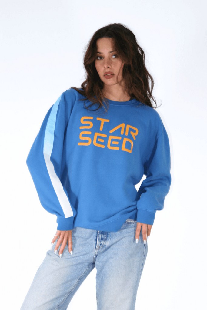 Woman posing in blue Starseed Crewneck sweatshirt by GFLApparel, symbolizing her celestial heritage, printed on it.