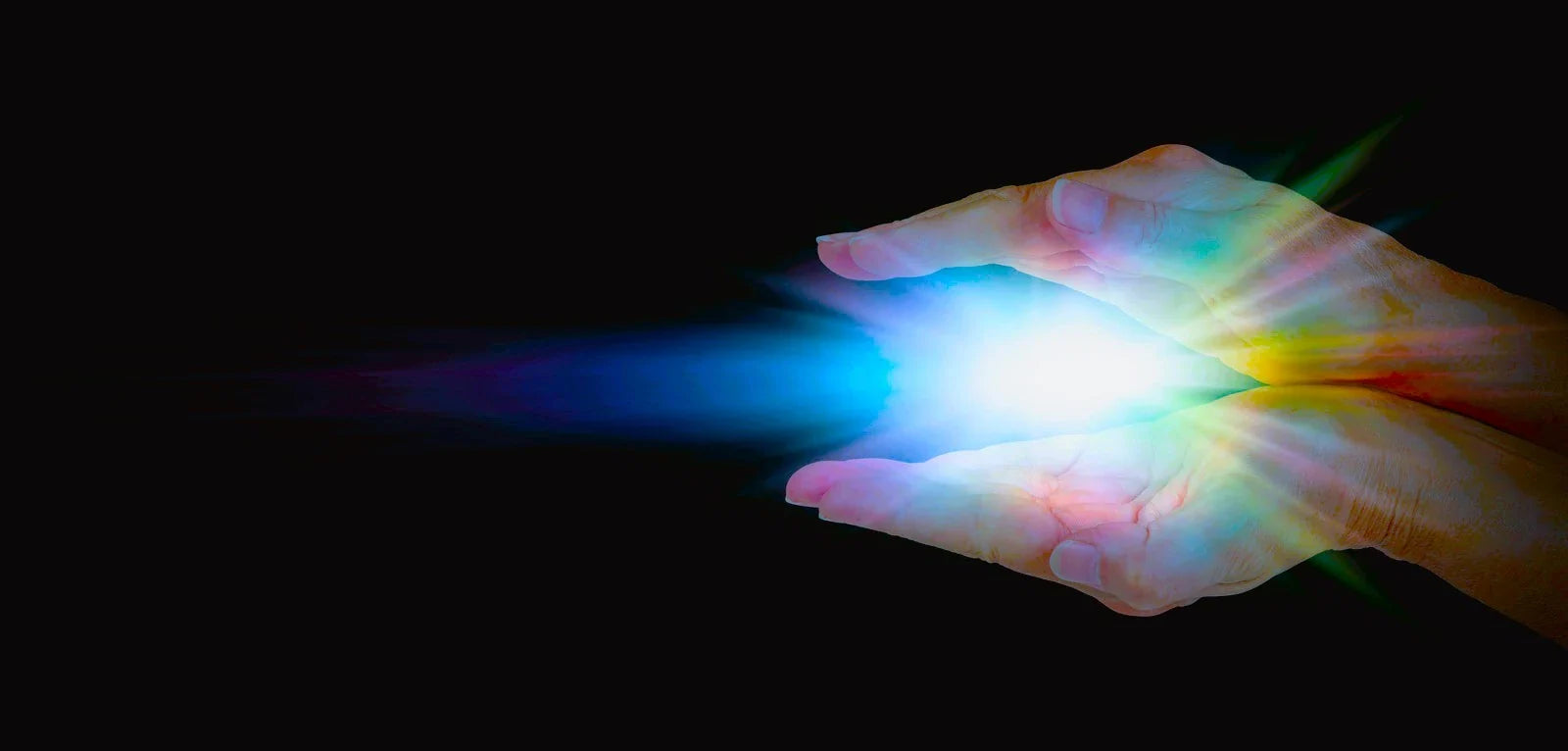 Colorful light emanating from hands on a black background